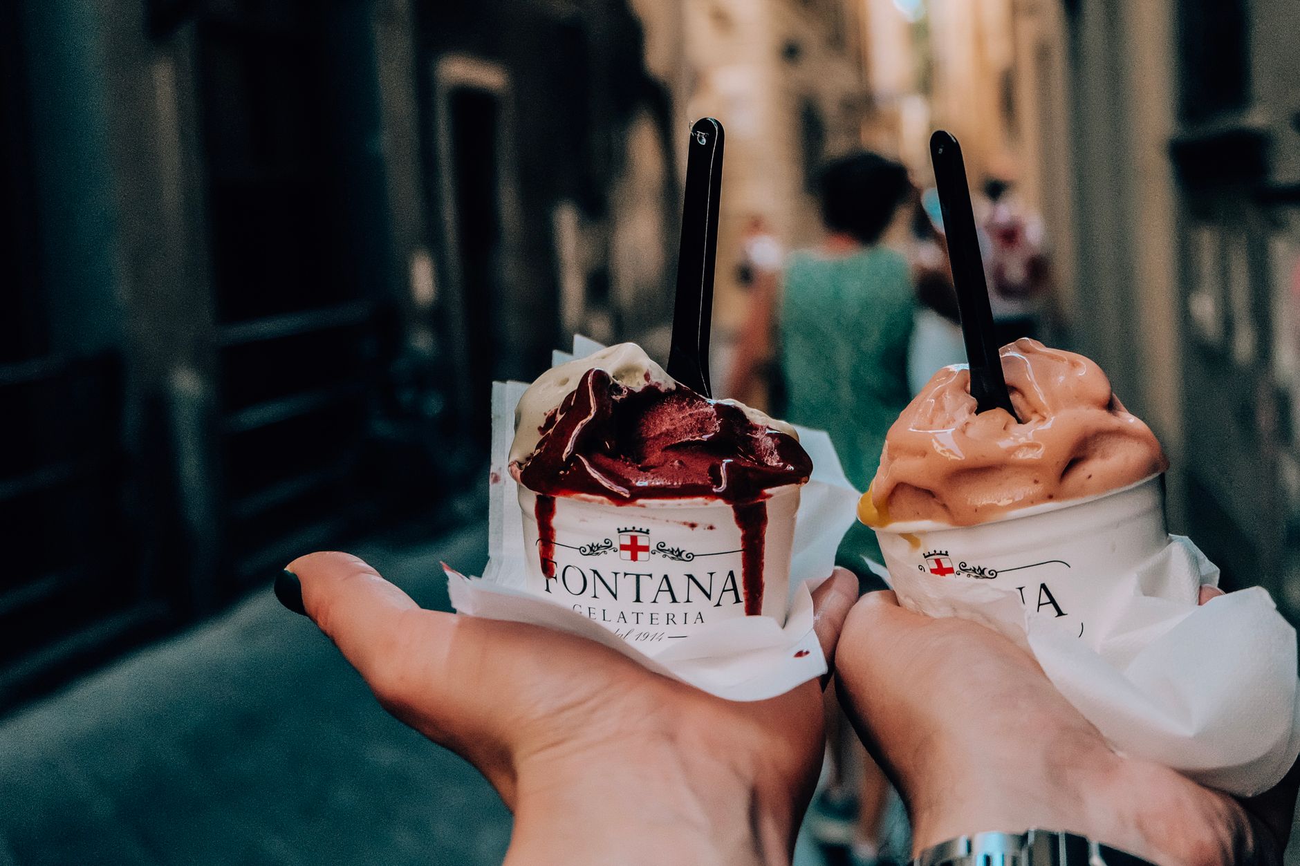 Couple with gelato walking down a narrow historic street in Italy
