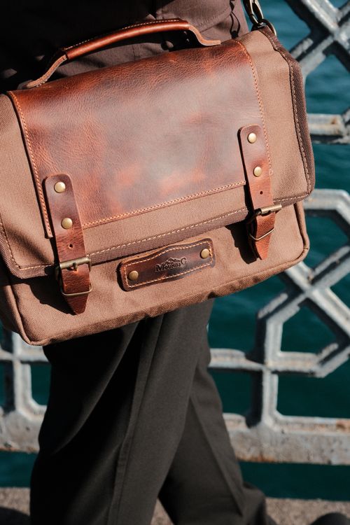 Free Close-up of a brown leather messenger bag carried by an adult on a bridge. Stock Photo