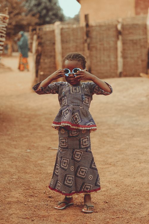 Free Child wearing traditional African dress and sunglasses, posing playfully outside. Stock Photo
