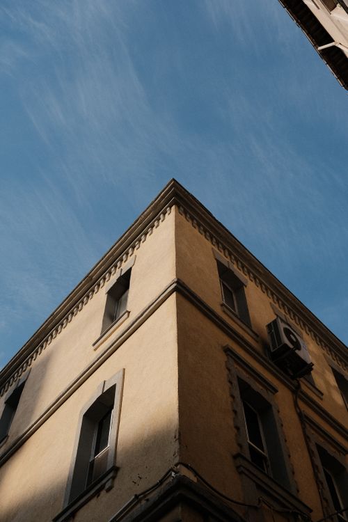 Free Low-angle view of a building corner with clear sky backdrop, capturing urban architecture. Stock Photo