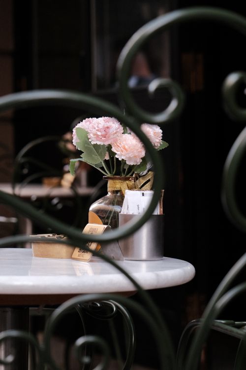 Free A charming café setting with pink flowers and elegant ironwork. Stock Photo