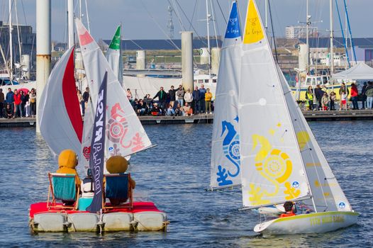 A vibrant sailing competition at Larmor-Plage, displaying colorful vessels and a lively crowd.
