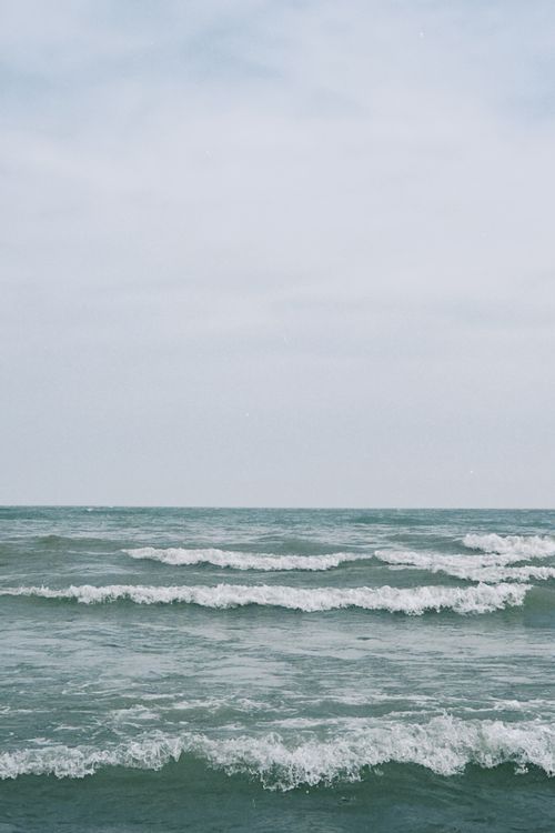 Free Calm ocean waves under a cloudy sky, perfect for serene landscapes. Stock Photo