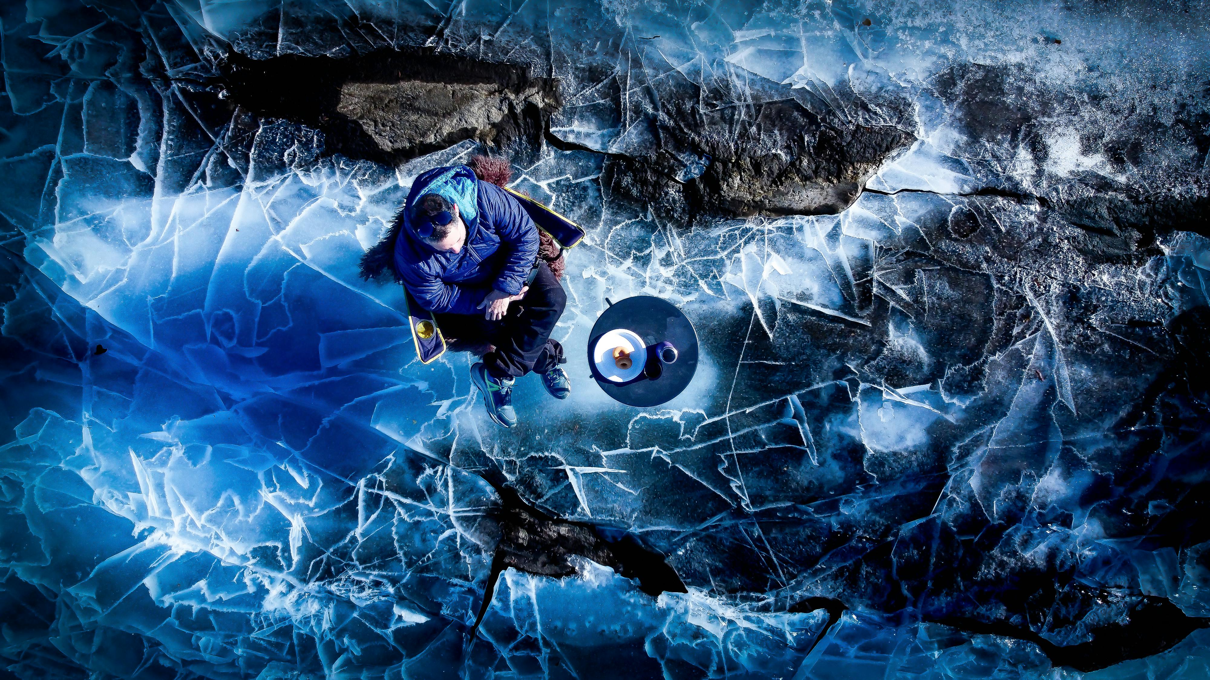 Gratuit Un homme en veste bleue est assis paisiblement sur un lac gelé, savourant la tranquillité d'un paysage hivernal norvégien. Photos