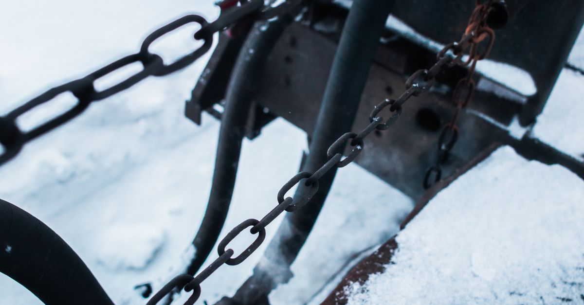 Detailed view of metal chains and equipment covered in snow during winter.