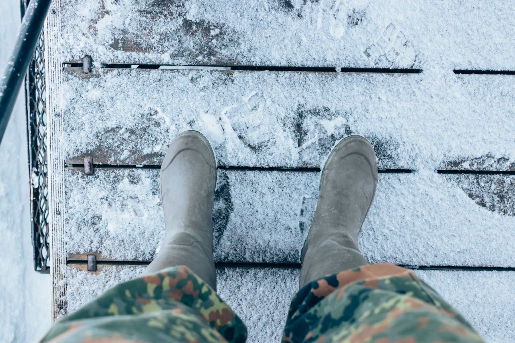 Winter boots on snowy wooden steps, seen from above