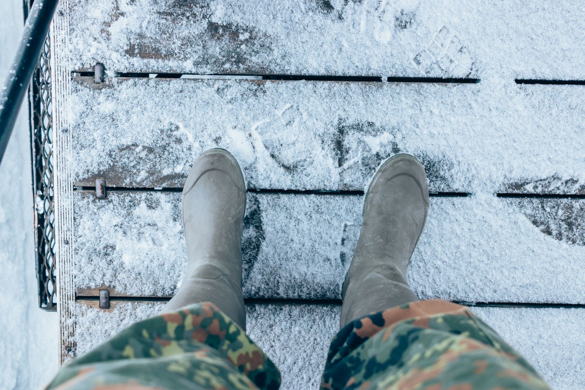 Winter boots on snowy wooden steps, seen from above