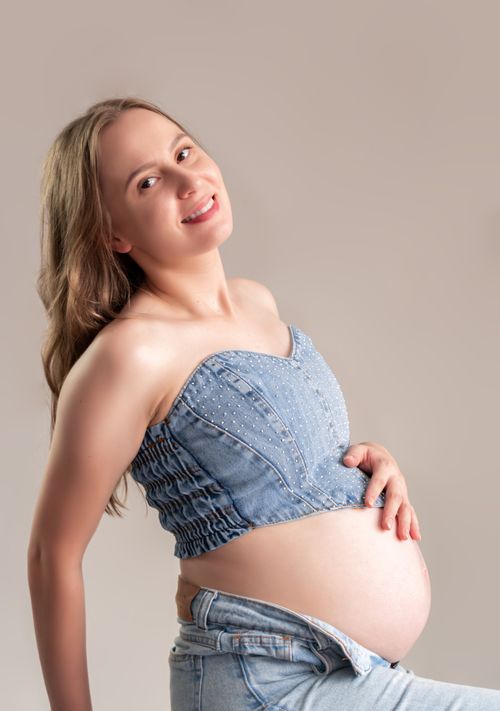 Free Joyful pregnant woman wearing denim top and jeans, exuding happiness and warmth. Stock Photo