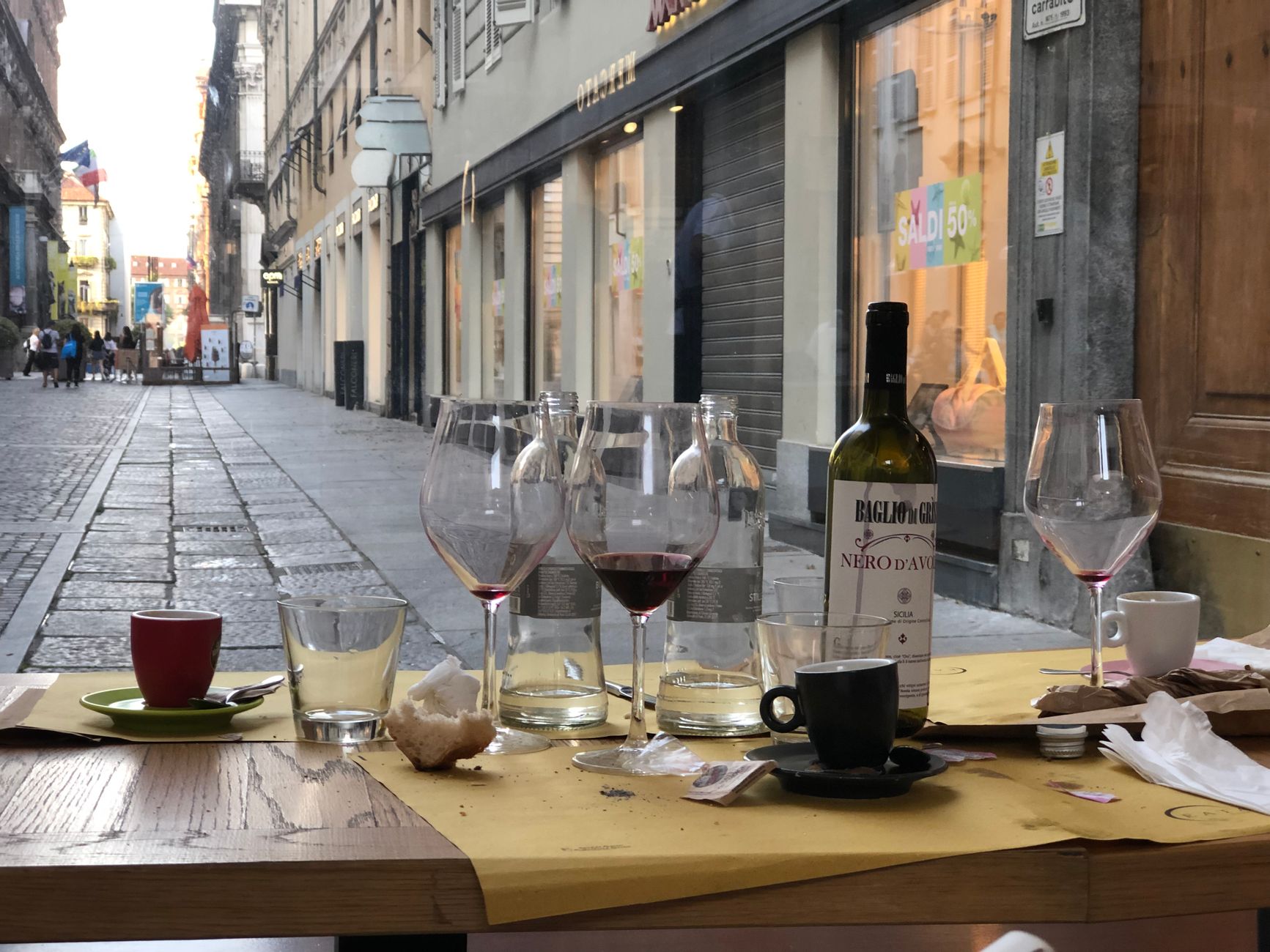 Empty wine glasses on a Turin street-side table