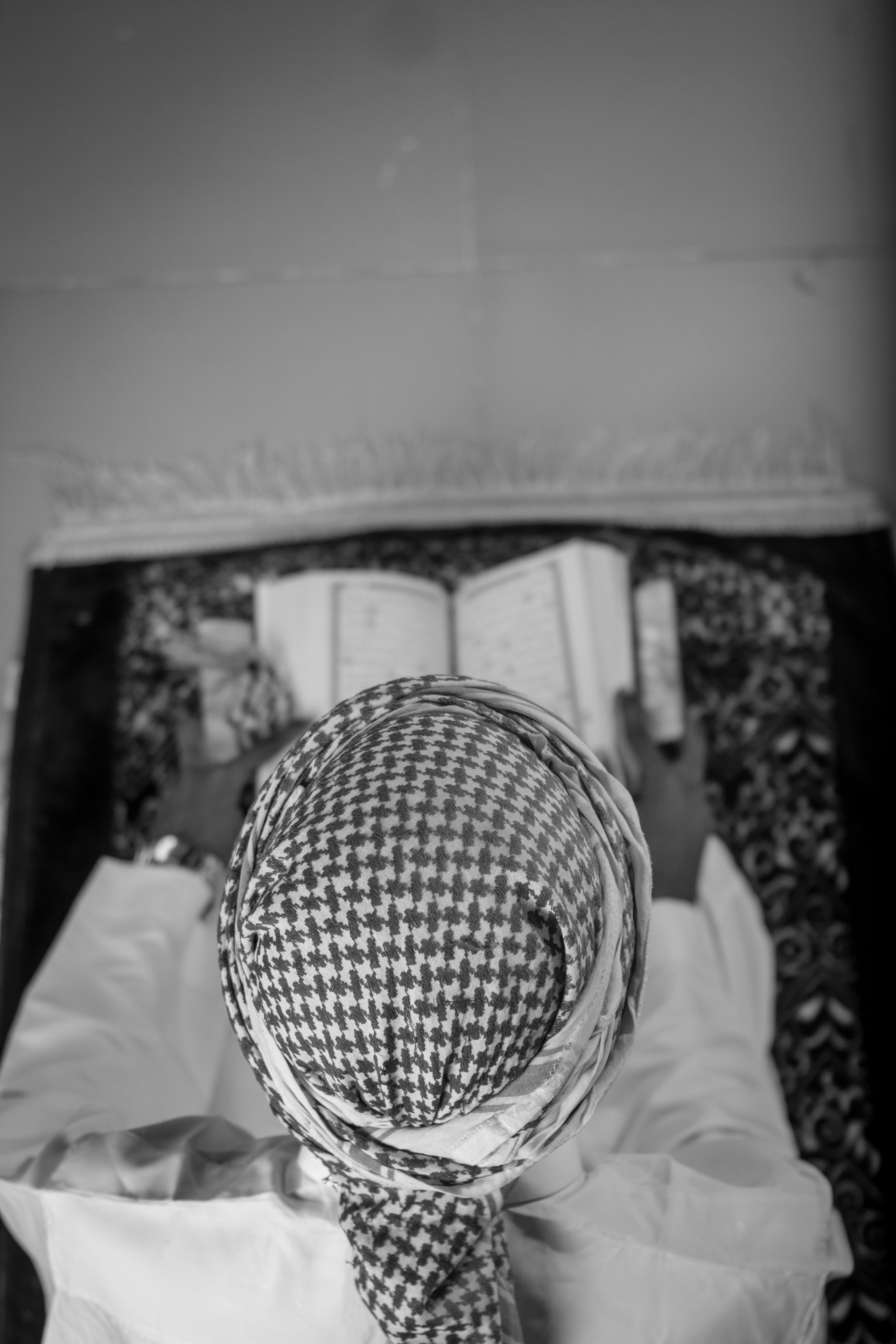 Free An overhead black and white image of a person reading a book on a prayer rug. Stock Photo