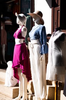 Stylish mannequins showcasing trendy summer outfits with hats in an outdoor market setting.
