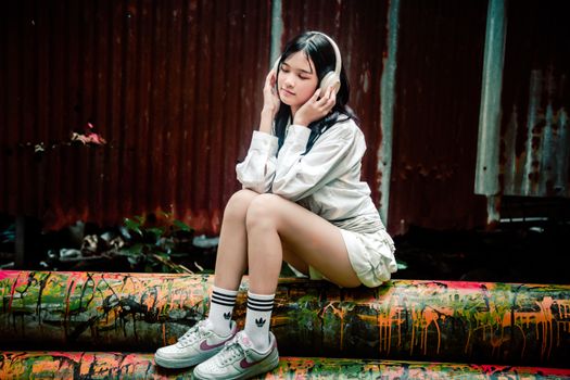 Young woman enjoying music with headphones in a vibrant urban environment.