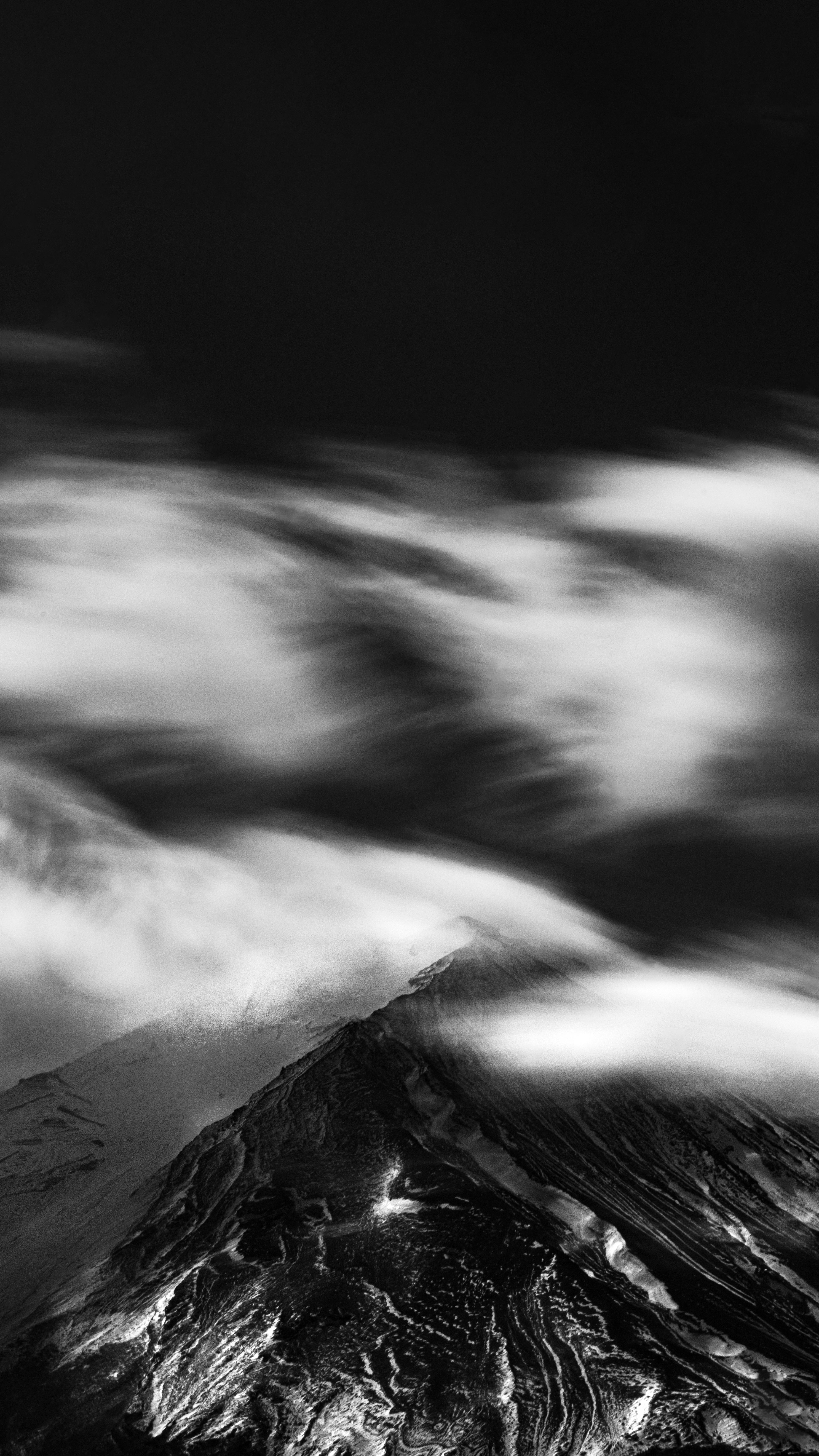 Stunning black and white photo of Mount Fuji with clouds, showcasing nature's power.