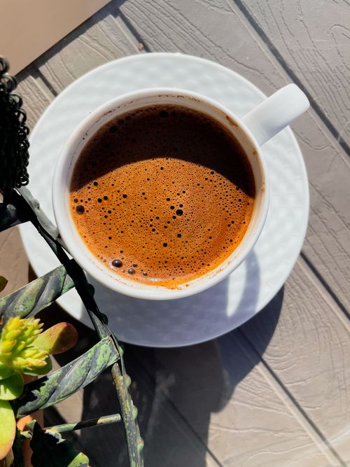 Free Overhead shot of a steaming cup of coffee on a table surrounded by plants. Stock Photo