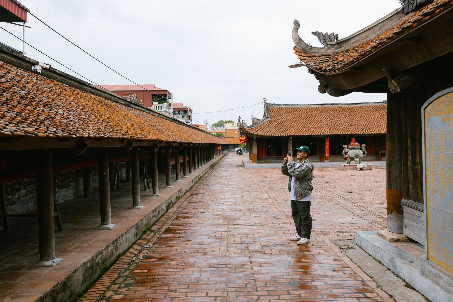 A man taking photos in the courtyard of a traditional temple with intricate architecture.