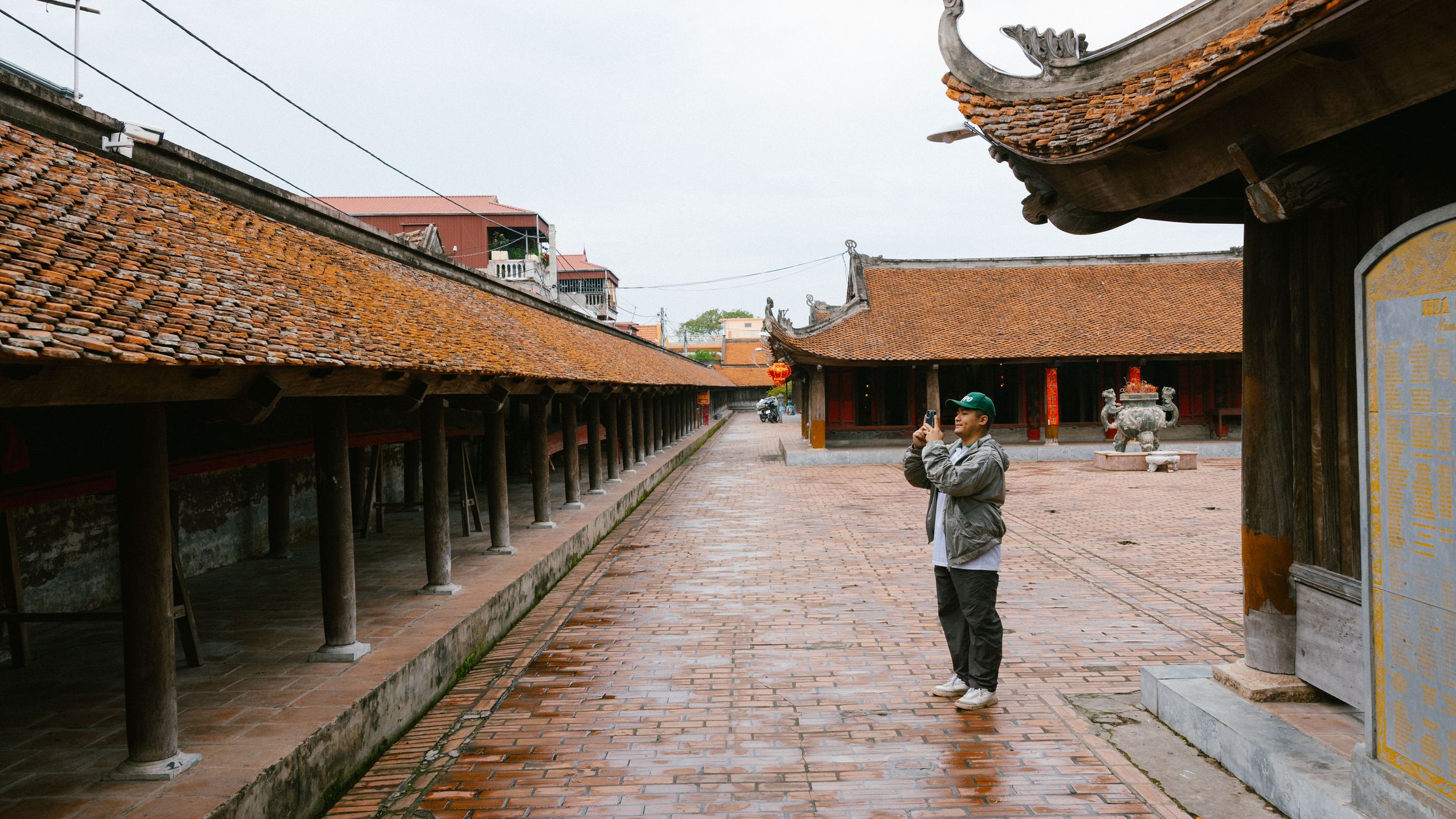 A man taking photos in the courtyard of a traditional temple with intricate architecture.