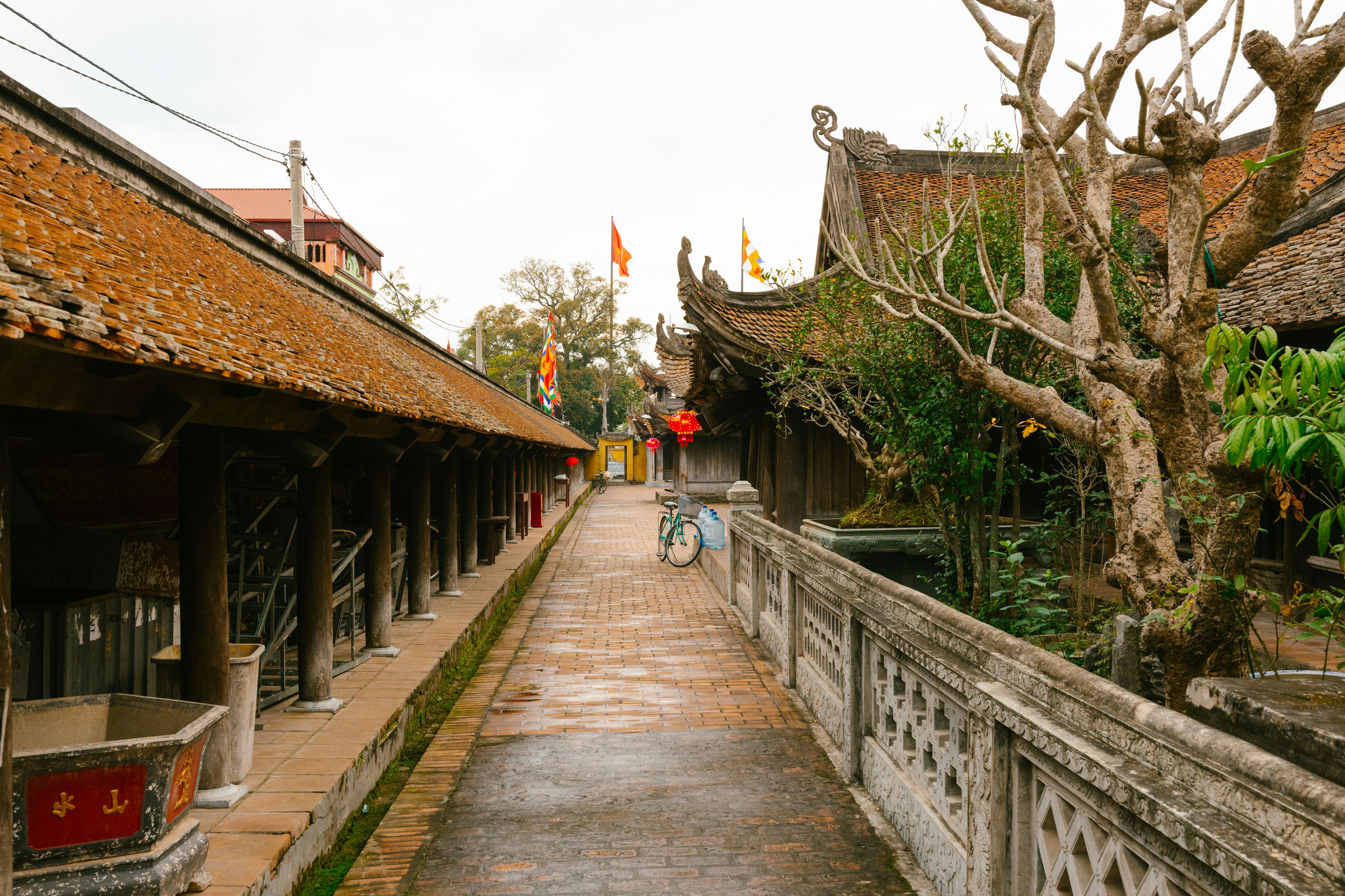 Traditional Vietnamese temple with serene pathway and cultural flags. Explore architectural beauty.
