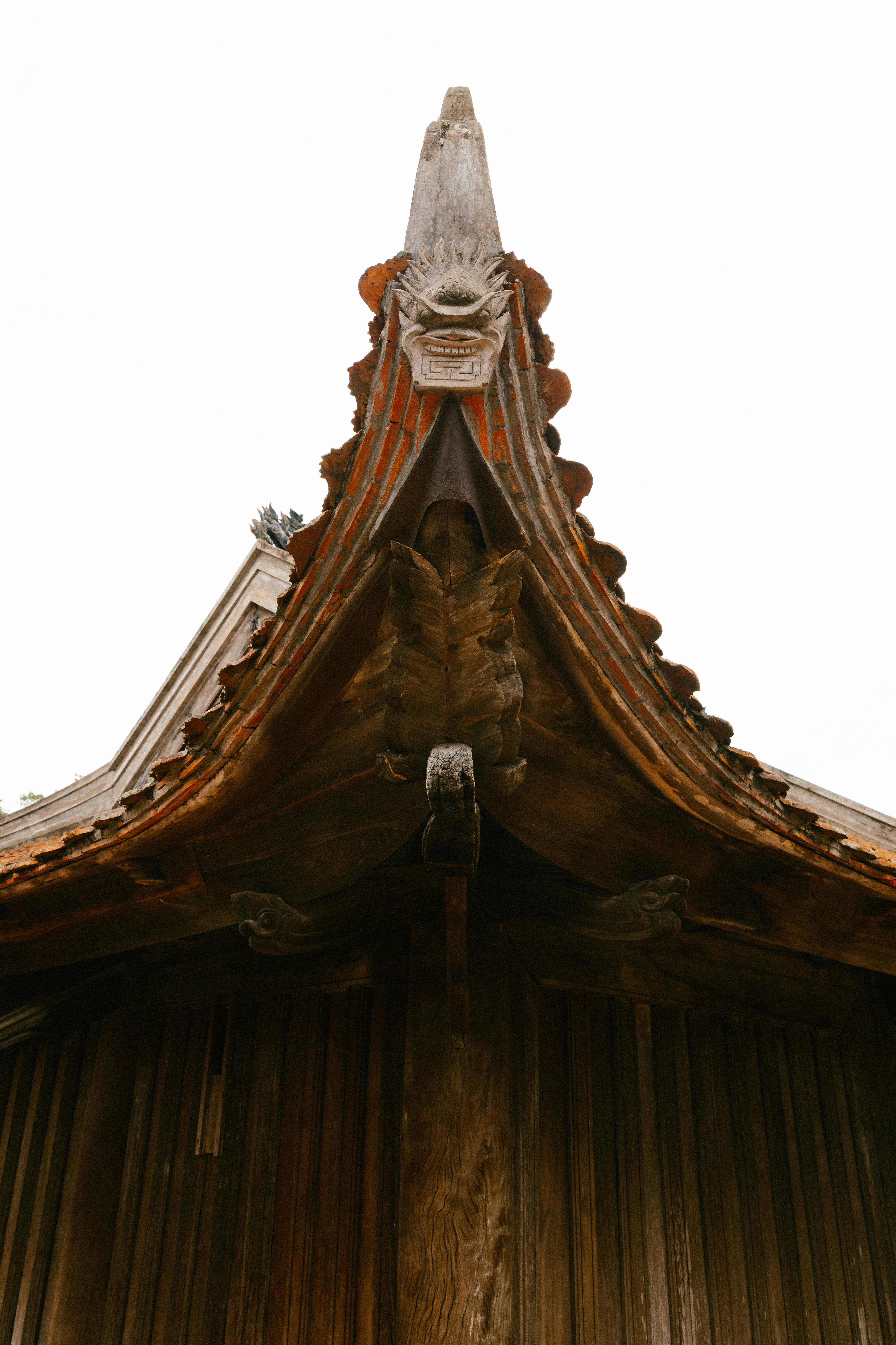 無料 複雑な彫刻とデザインが施された伝統的な木造寺院の屋根の魅惑的な眺め。 写真素材