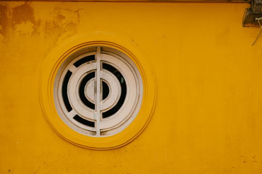 A round window set in a bright yellow wall, showcasing minimalistic and modern architecture.