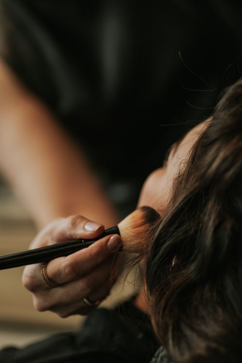 Free Close-up view of a professional makeup artist applying blush on a woman's face. Stock Photo