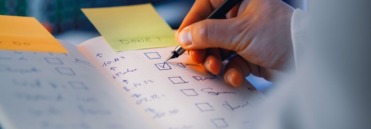 A hand writing a checklist in a notebook