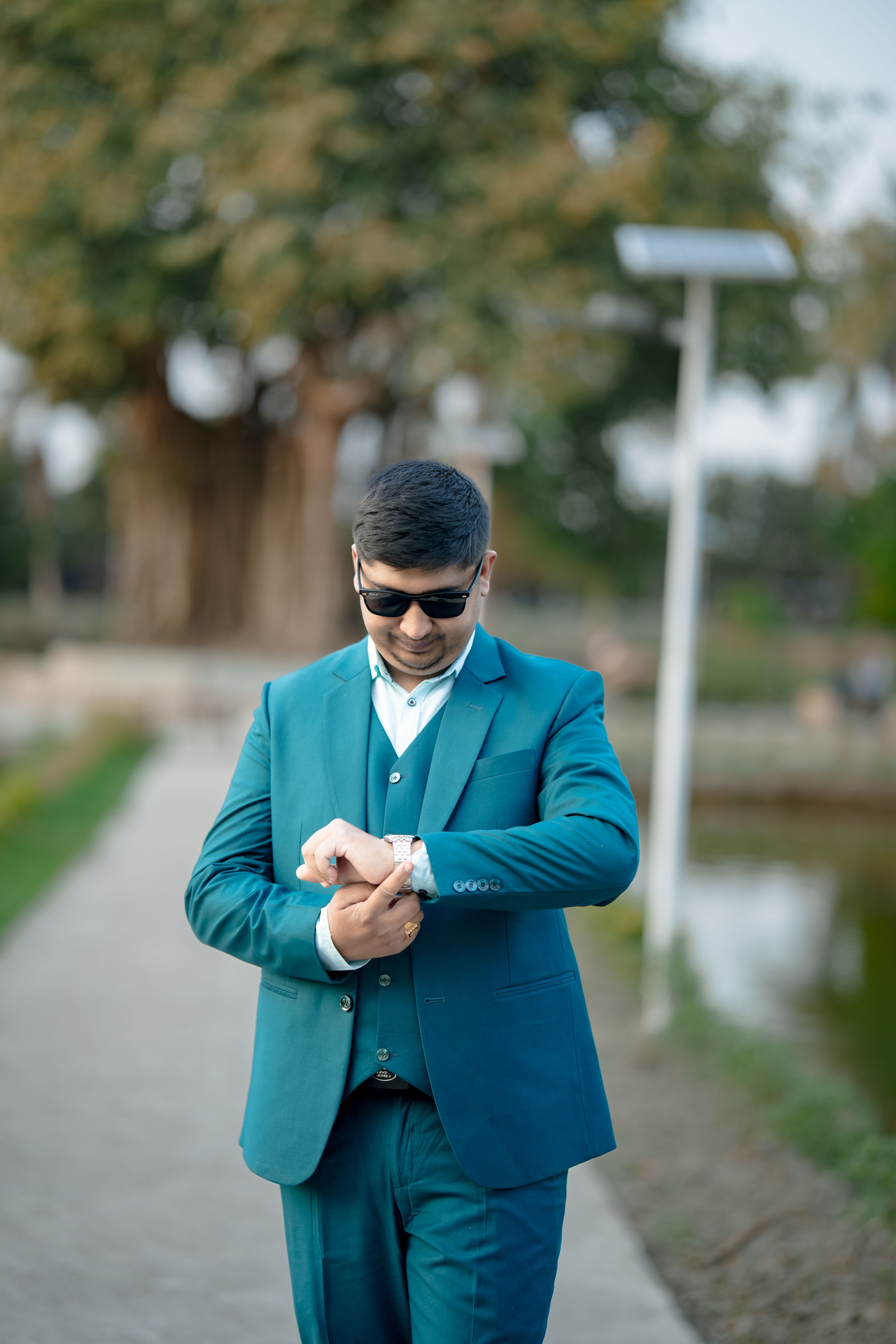 Gratis Un uomo alla moda all'aperto, con un abito blu e occhiali da sole, controlla l'orologio. Foto a disposizione
