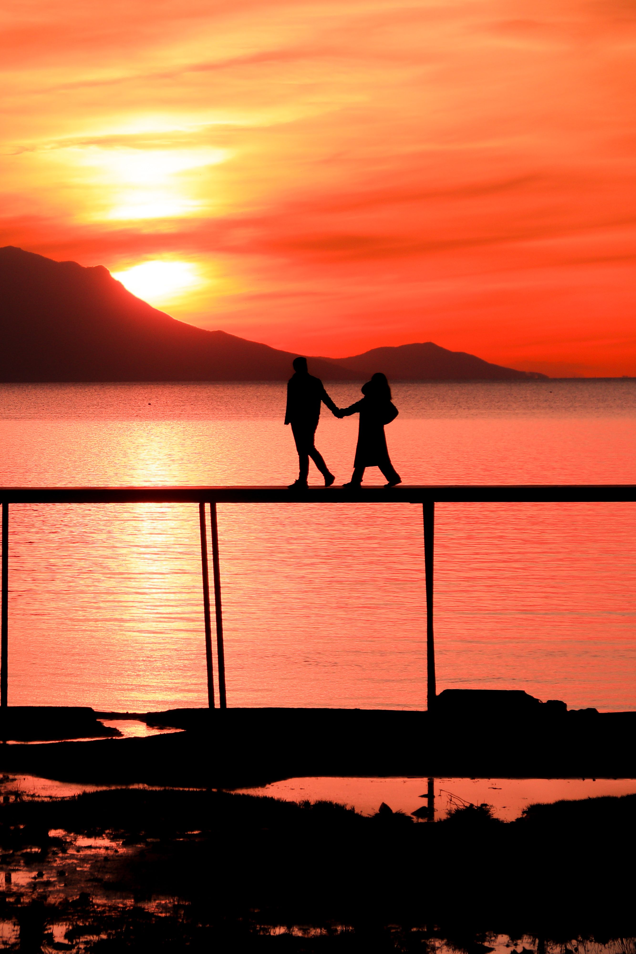 Silhouette of Couple Walking on Pier at Sunset · Free Stock Photo