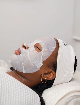 A serene woman receiving a hydrating sheet mask facial treatment in a spa setting.