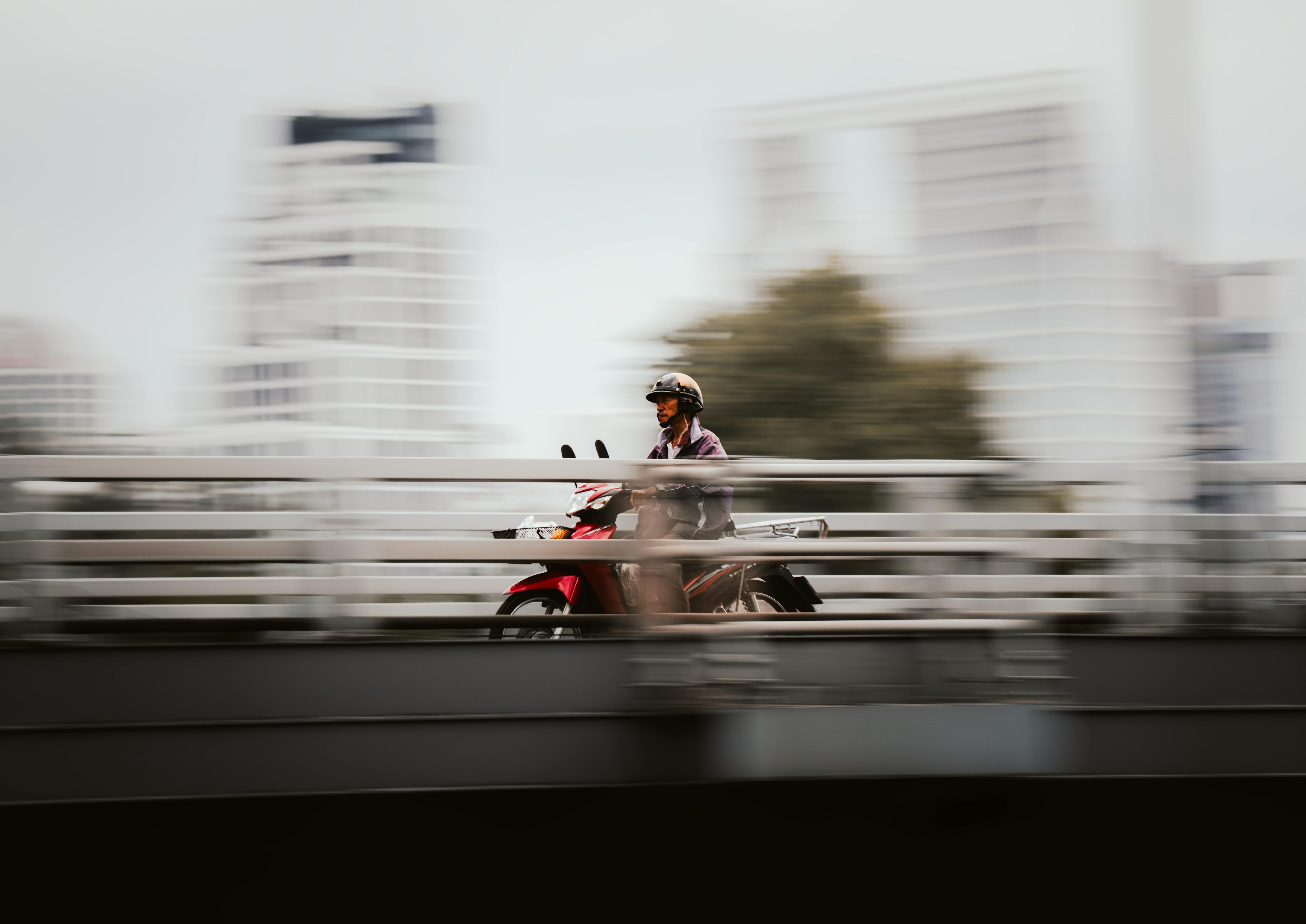 Ilmainen Sumennettu panorointikuva moottoripyöräilijästä, joka kiitää Bangkokissa ja tallentaa kaupunkien energiaa. Kuvapankkikuva