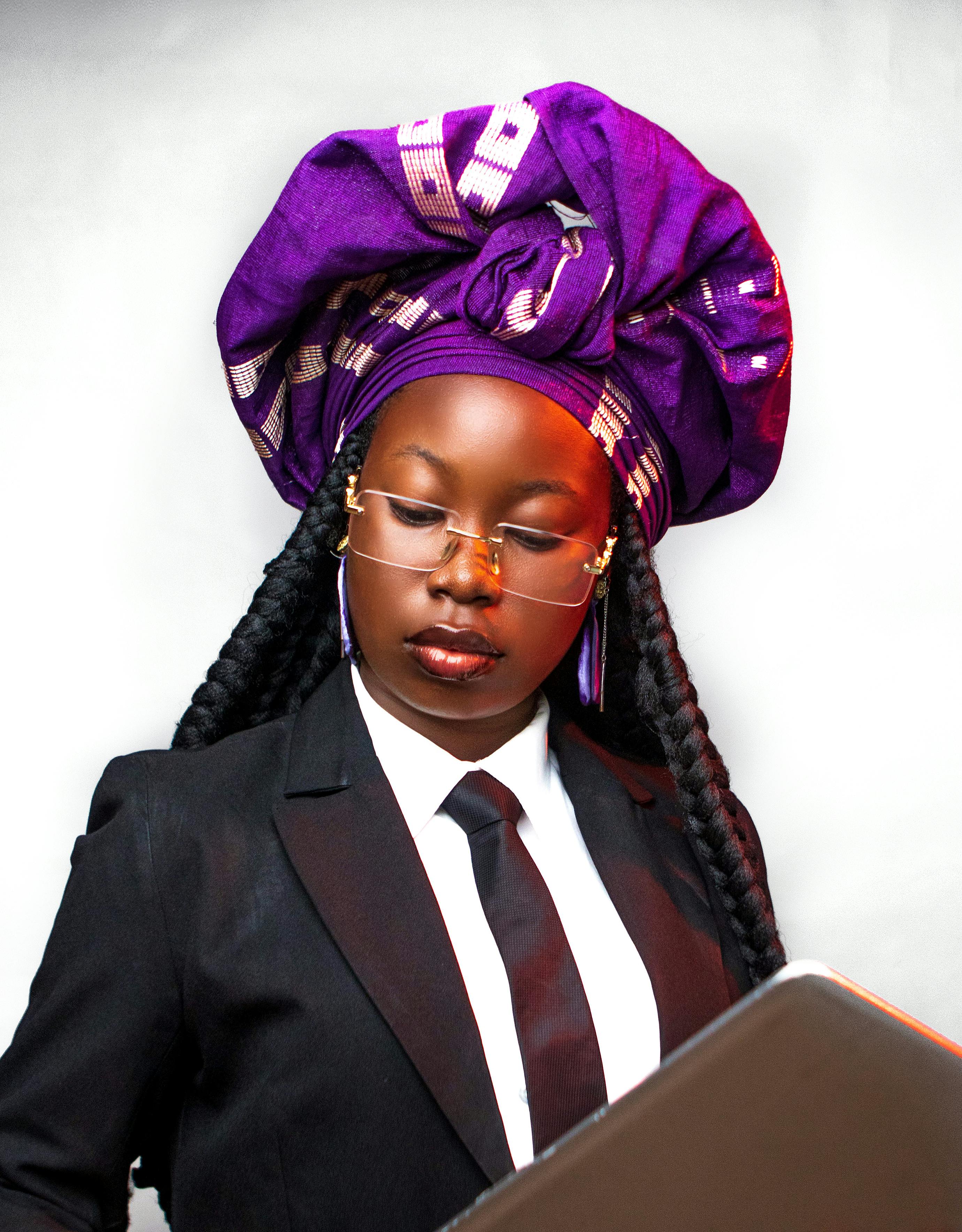 Portrait of an African businesswoman in a suit wearing a vibrant traditional headwrap.