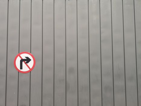 No right turn road sign on a textured grey wall with vertical planks.