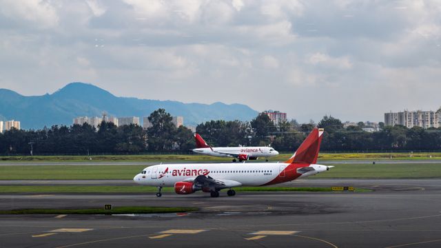 Avianca passenger aircraft on the runway at Bogotá, Colombia airport with city and mountains in background. — lounges at Bogota Airport