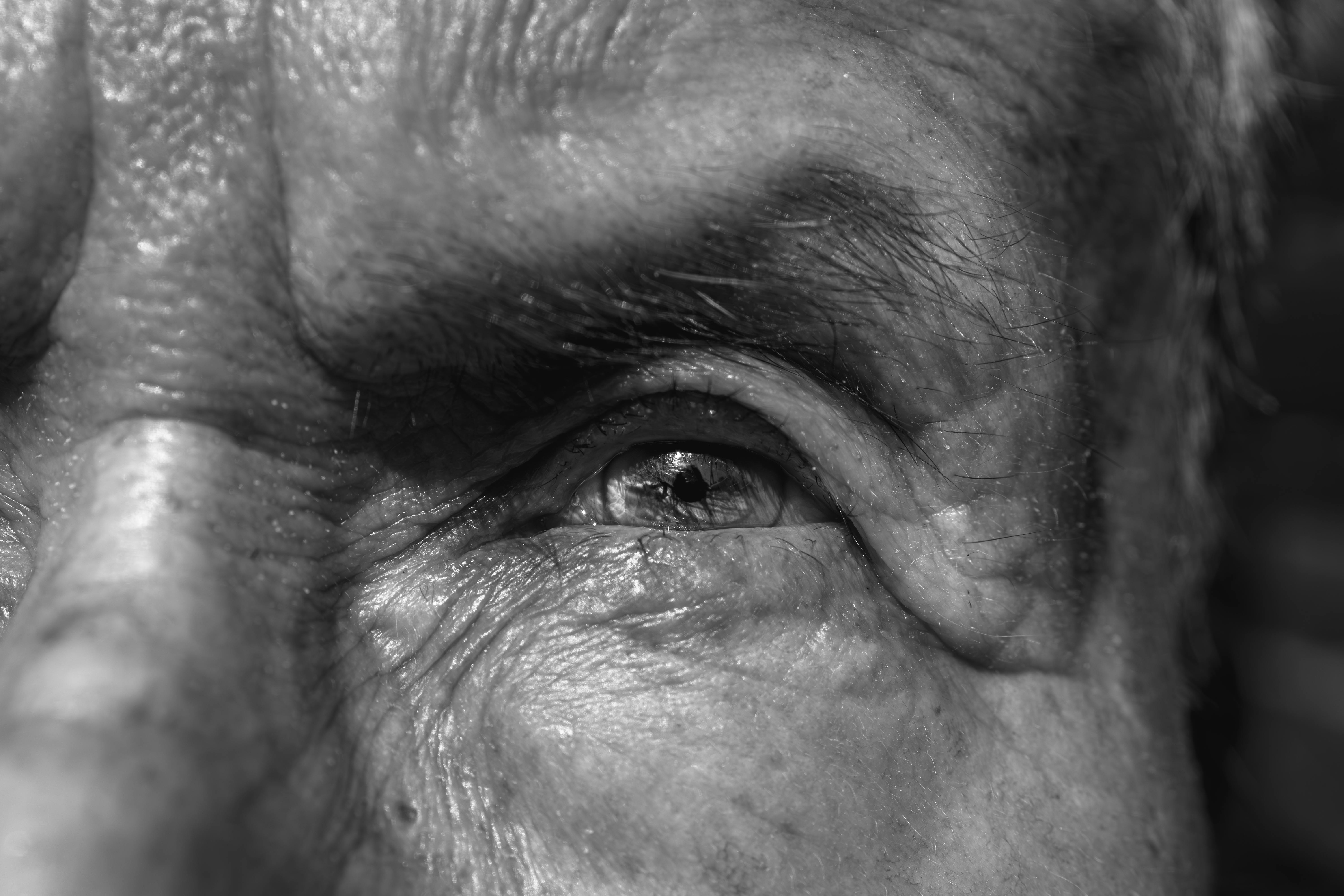 Detailed black and white close-up of an elderly man's eye, capturing texture and emotion.