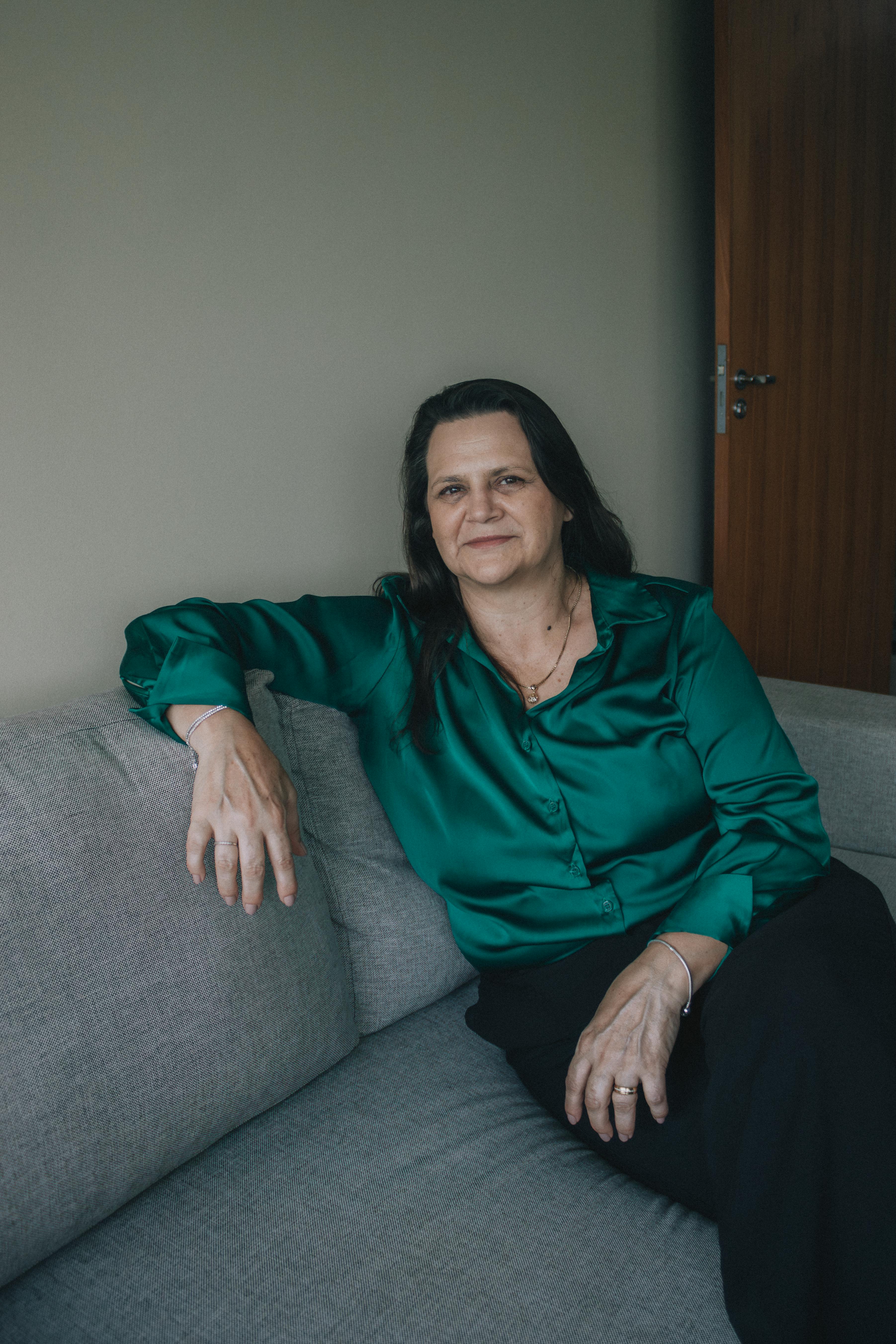 Portrait of a woman in a green shirt relaxing on a sofa indoors.