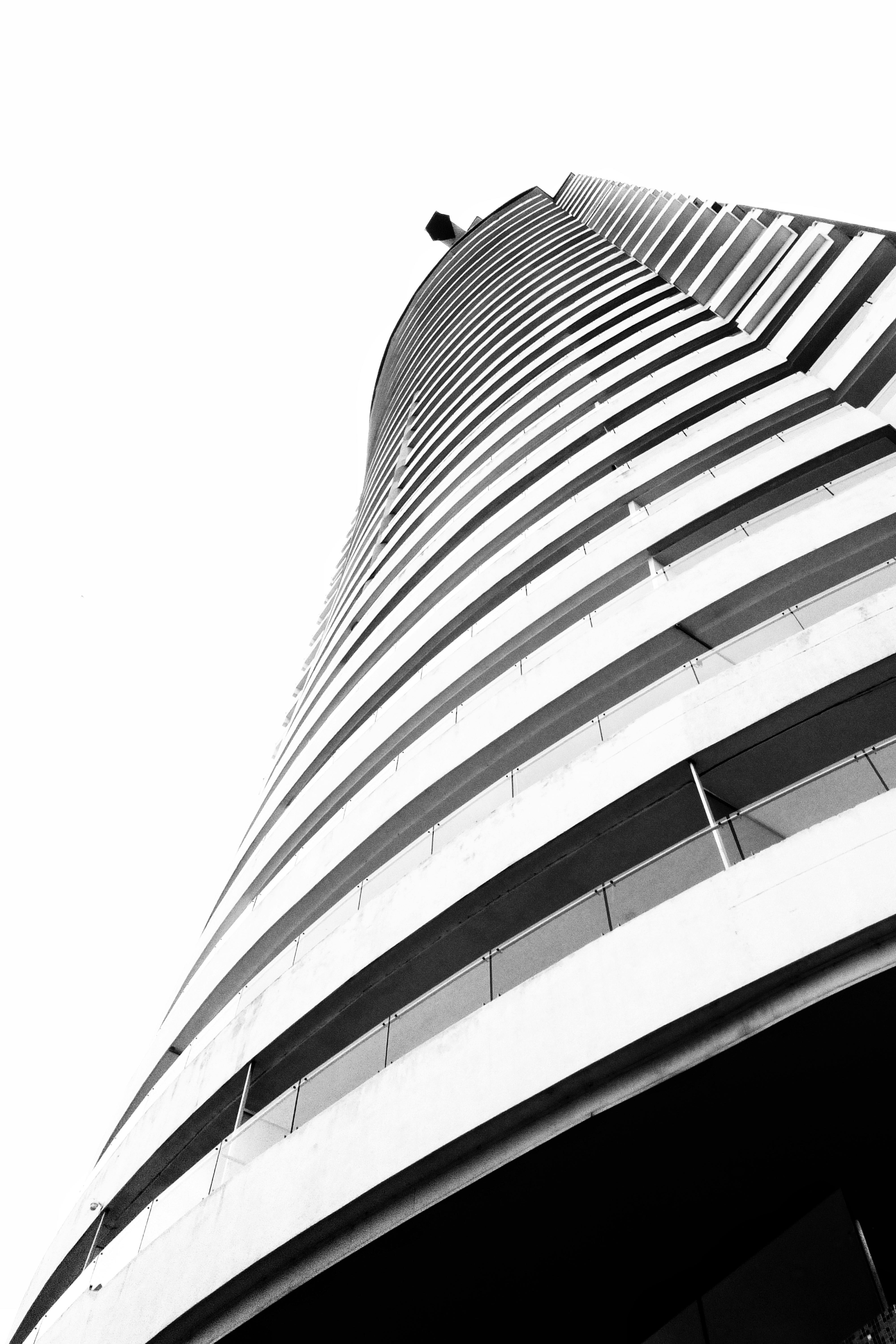 De franc Una impressionant imatge en blanc i negre d'un gratacel modern vist des de baix, que mostra el seu disseny corbat. Foto d'estoc