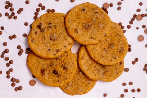 Free Close-up view of freshly baked chocolate chip cookies surrounded by chocolate chips. Stock Photo