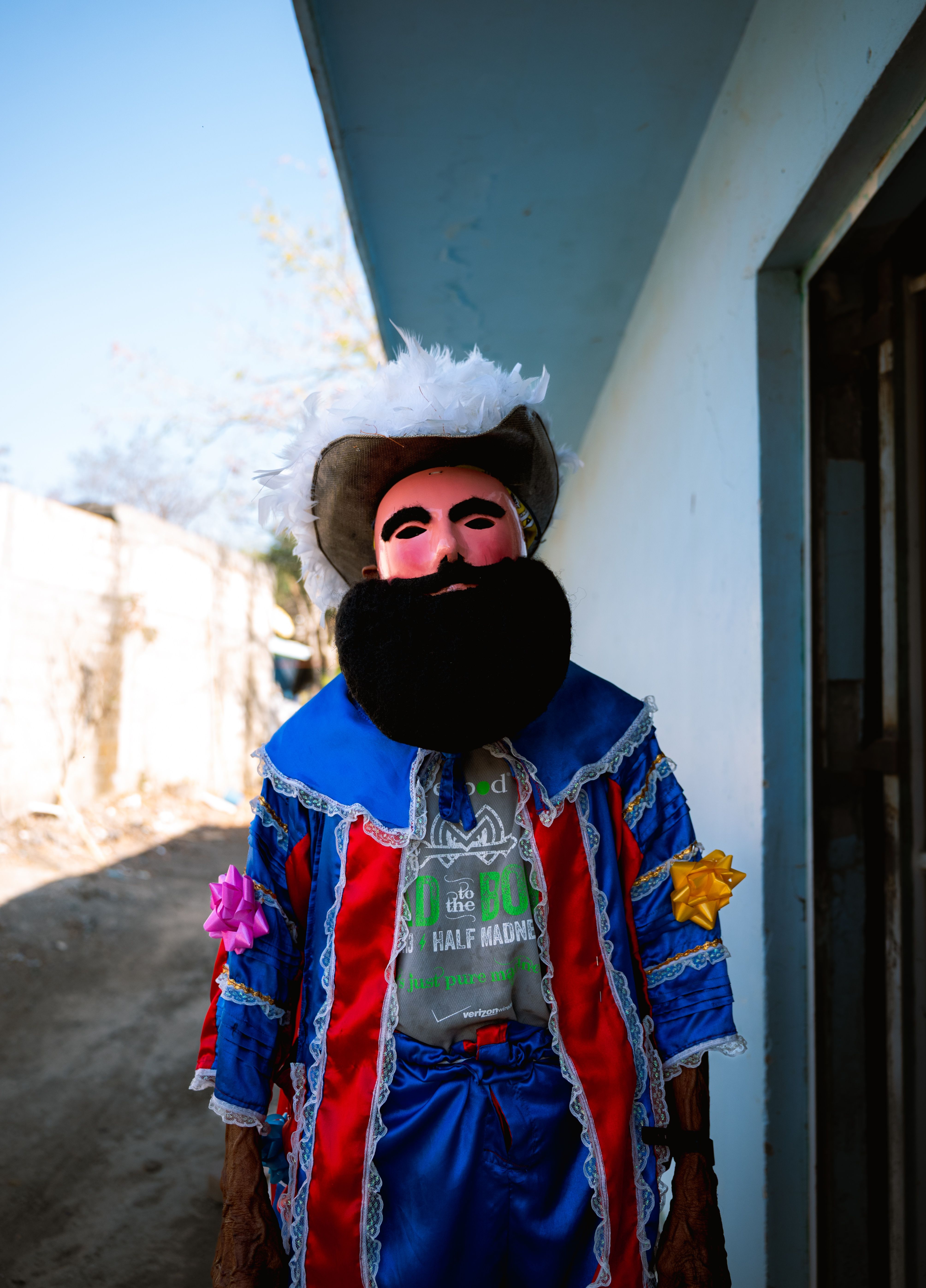 A performer dressed in colorful costume and mask at an outdoor festival.