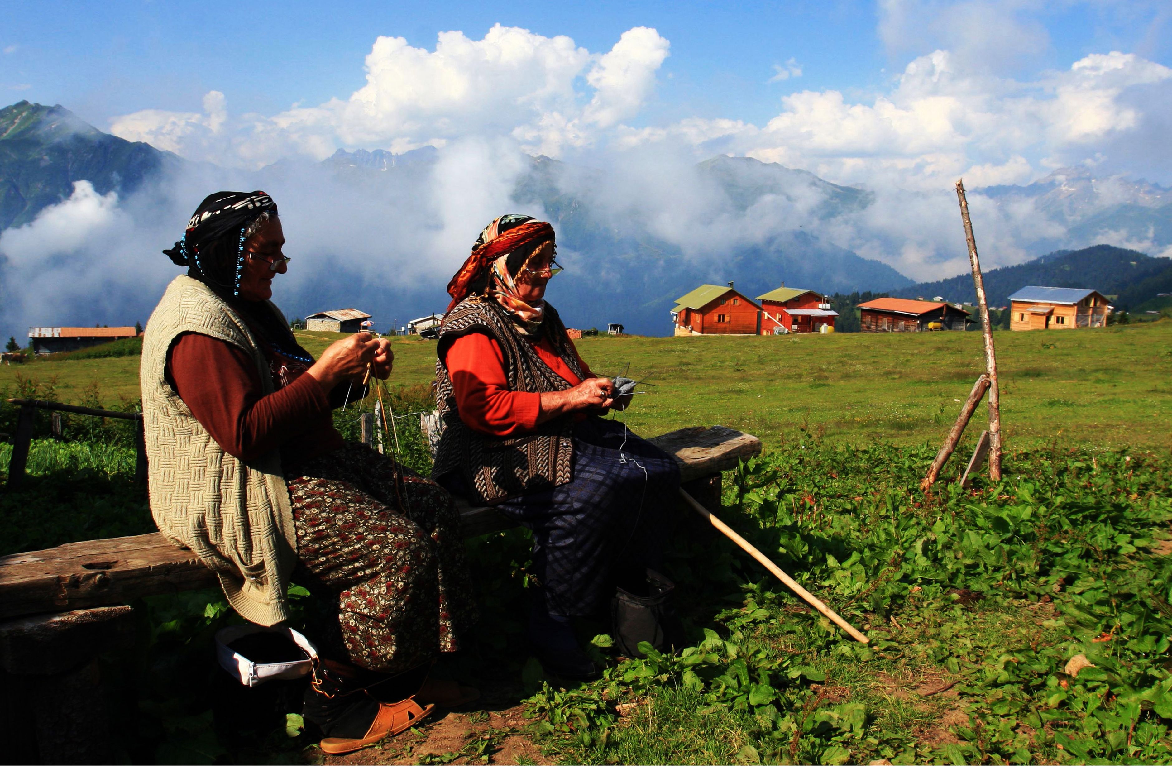 Elderly women knitting in the Rize highlands, Türkiye, with scenic mountain views.