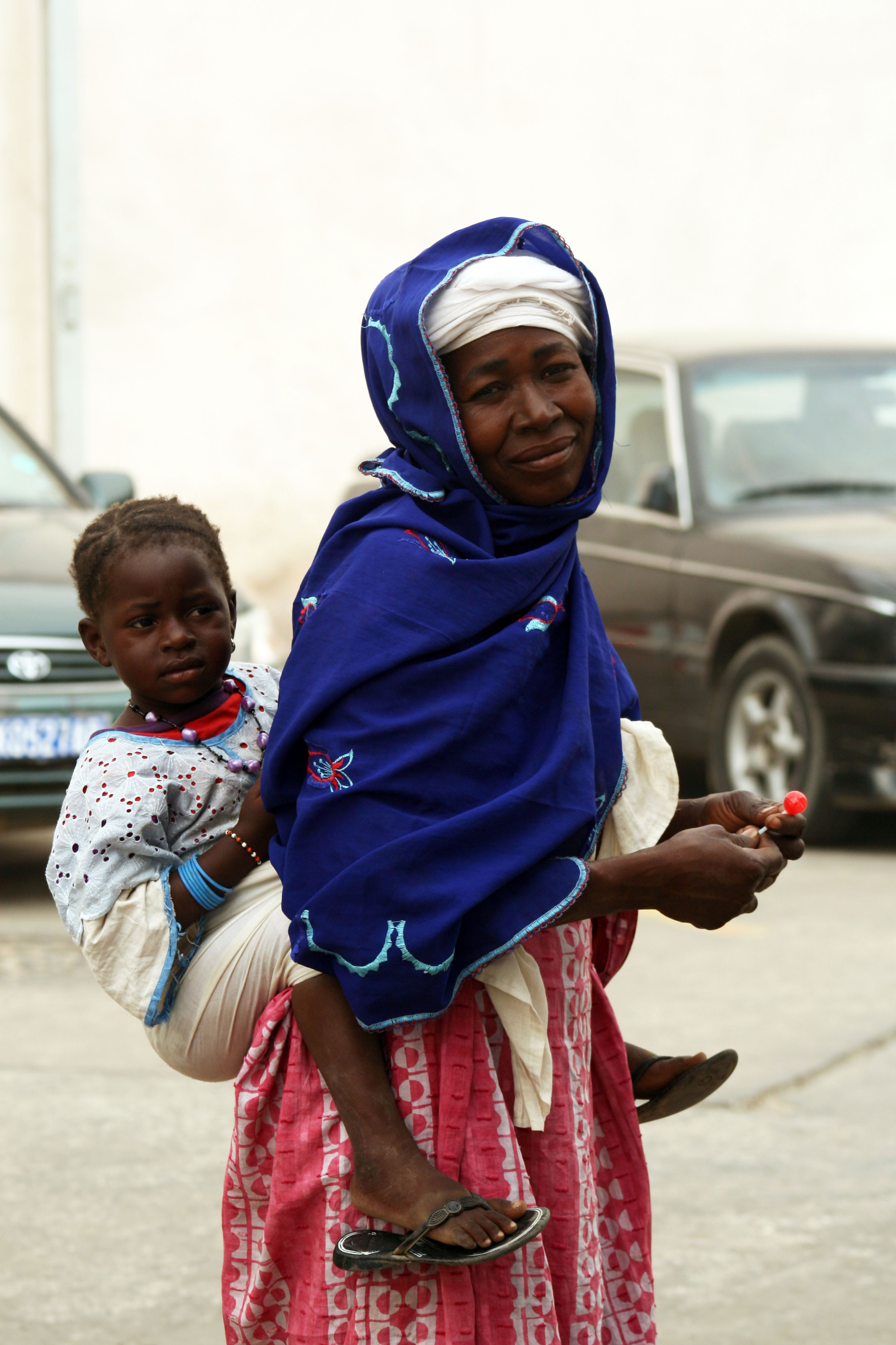 A woman in traditional attire carries her child in Saint-Louis, Senegal.