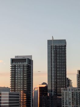 Beautiful view of Toronto's skyline at sunset with a plane flying. Modern architecture with warm tones.