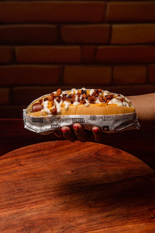Free Delicious gourmet hot dog topped with melted cheese and crumbled bacon, perfect for food lovers. Stock Photo