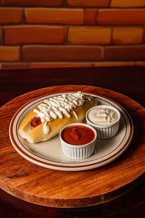 Free A delectable hot dog drizzled with mayonnaise, served with ketchup and creamy sauce on the side. Stock Photo