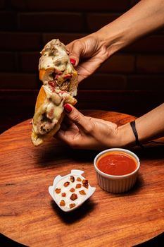 Delicious gourmet sandwich with cheese and dipping sauce on a wooden platter.