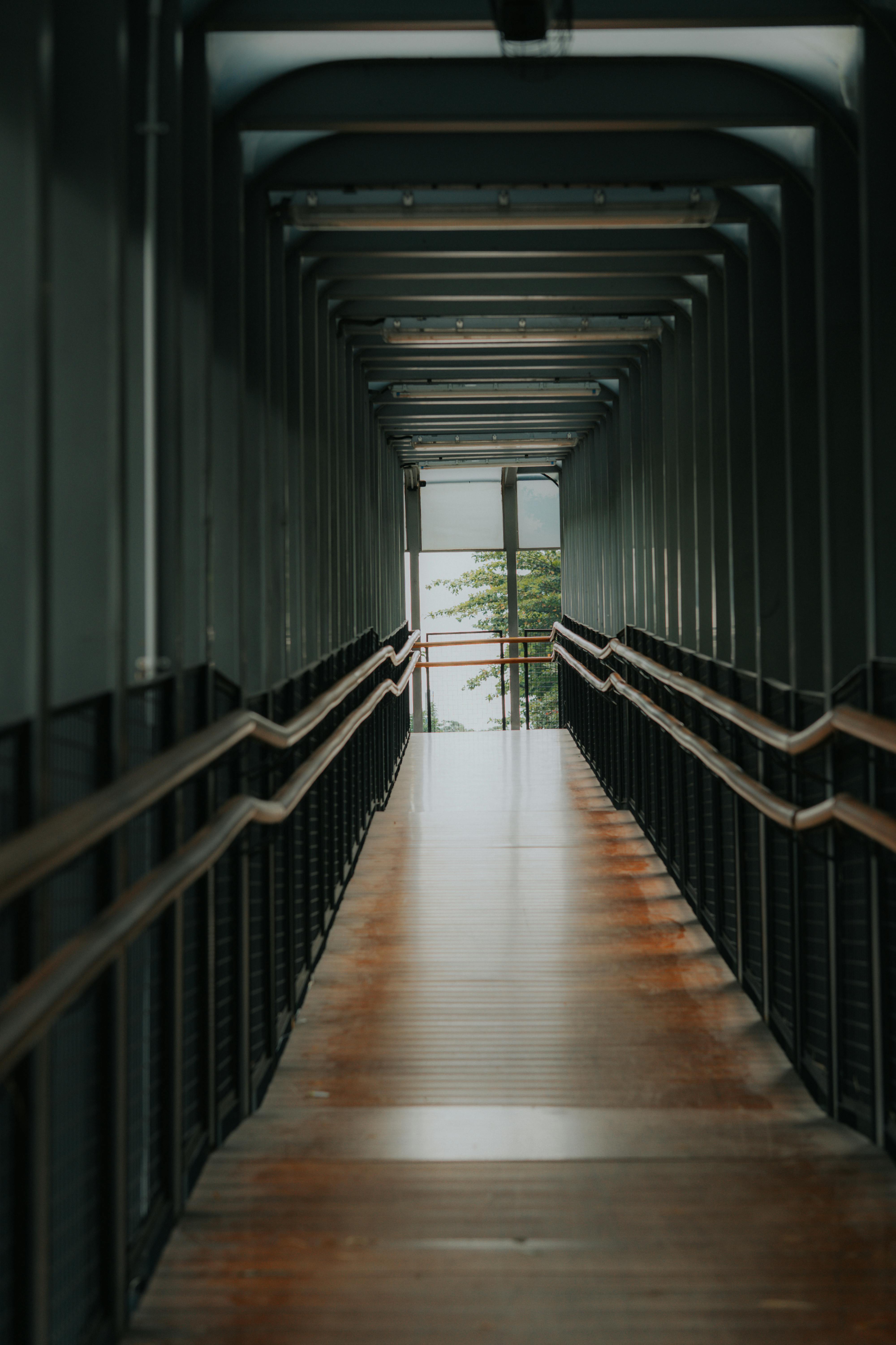 gratis Lange, overdekte gang met een modern architectonisch ontwerp, veel natuurlijk licht en een groen uitzicht aan het einde. Stockfoto