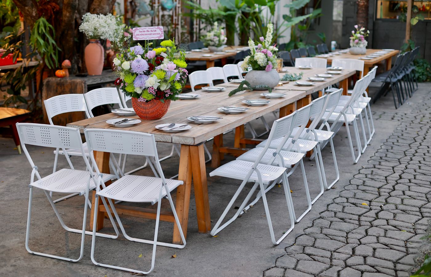 Stylish outdoor dining setup featuring floral centerpieces and white chairs.