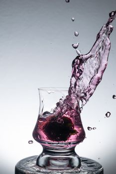 Dramatic splash of purple liquid in a glass, creating dynamic motion and elegance.