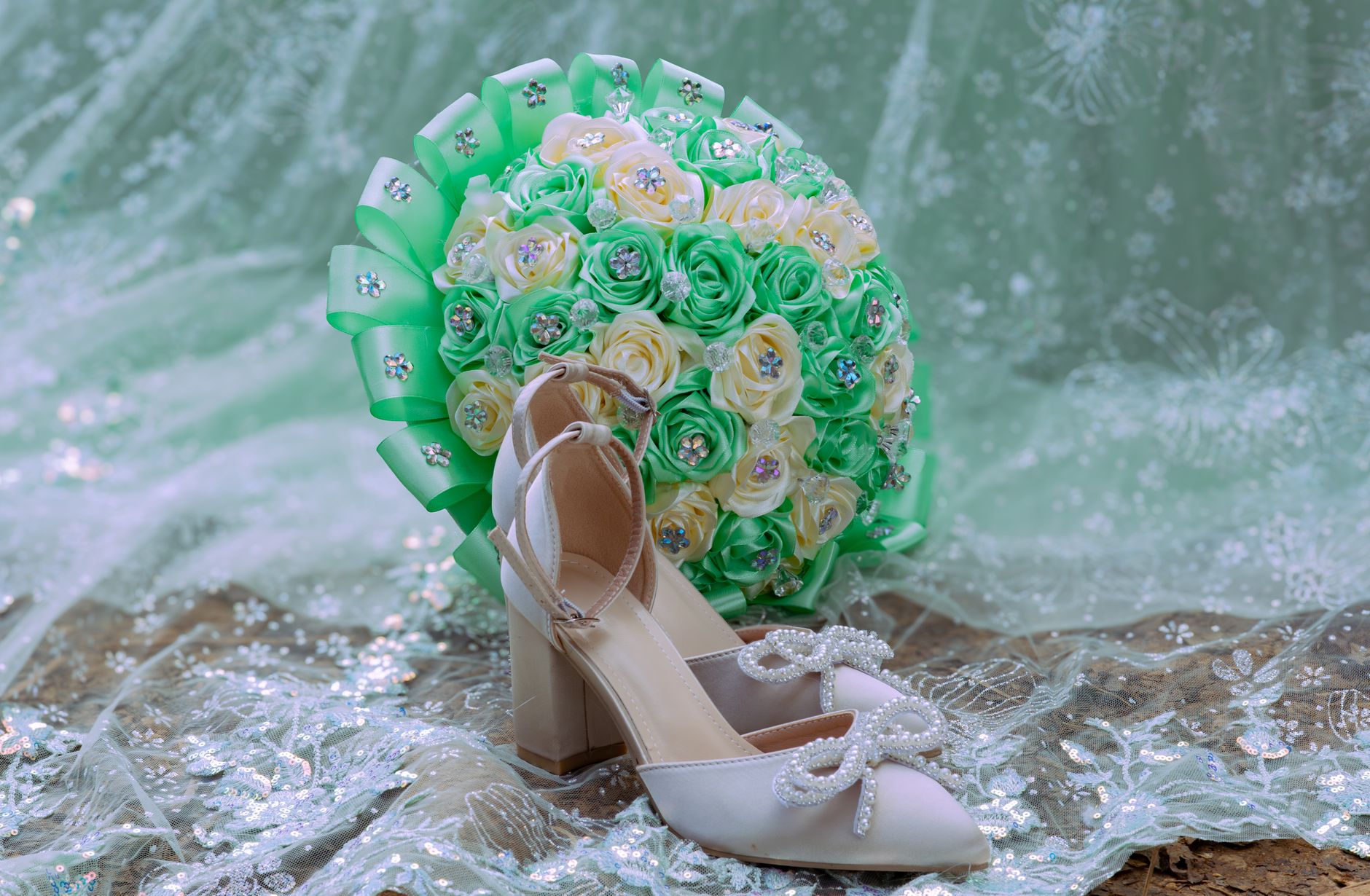Elegant white bridal shoes with pearl accents paired with a vibrant green and white rose bouquet.