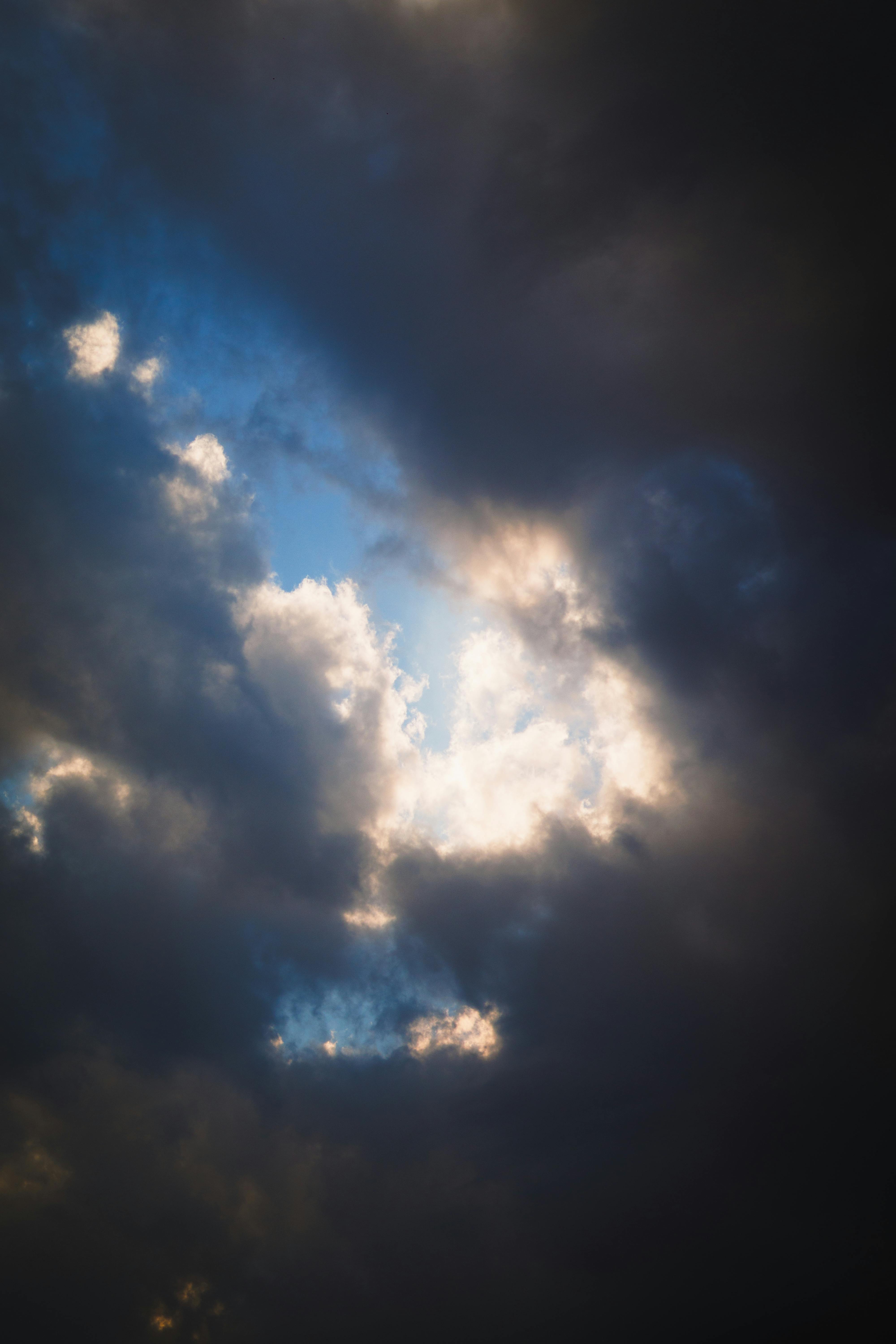 Free Captivating sky with billowing clouds and sunlight piercing through, creating a dramatic scene. Stock Photo