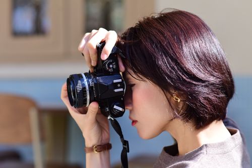 Free A young woman capturing moments with a vintage camera indoors. Stock Photo