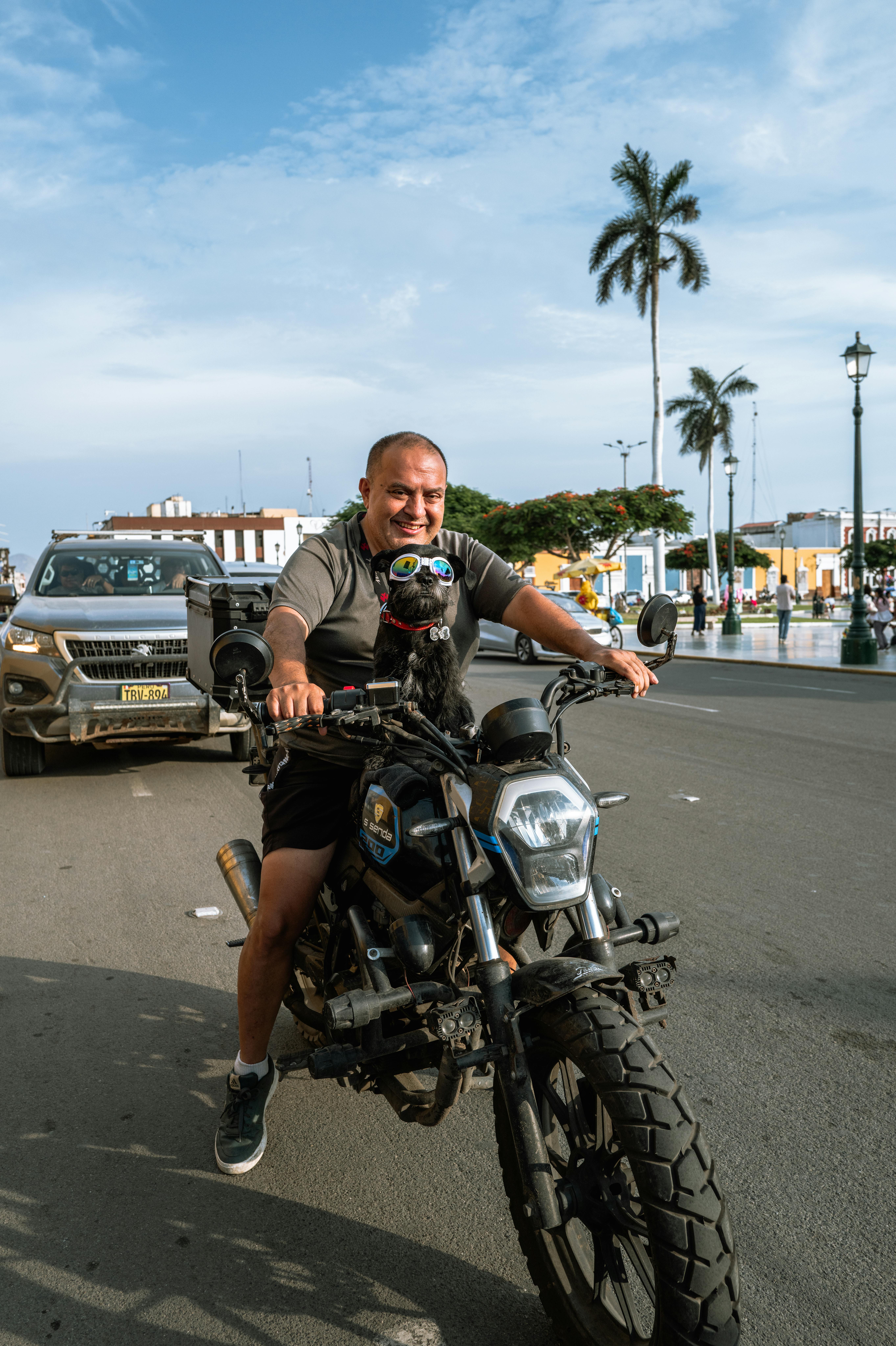 A man riding a motorcycle on a busy street in Trujillo, Peru, capturing urban life.